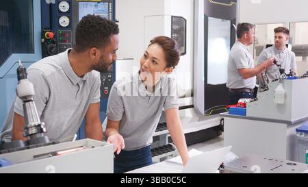 Male And Female Engineers Discussing Plans For Job Whilst Looking At Laptop Stock Photo
