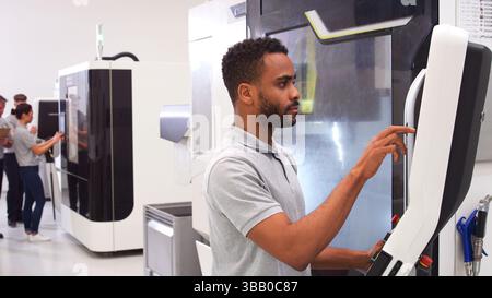 Male Engineer Or Apprentice Using CNC Machine In Factory Stock Photo