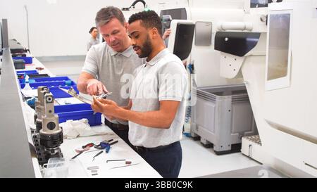 Engineer And Male Apprentice Measuring Components In Hi Tech Engineering Plant Stock Photo
