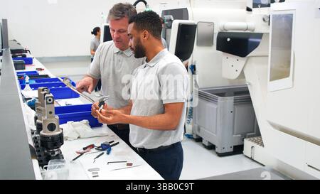 Engineer And Male Apprentice Measuring Components In Hi Tech Engineering Plant Stock Photo