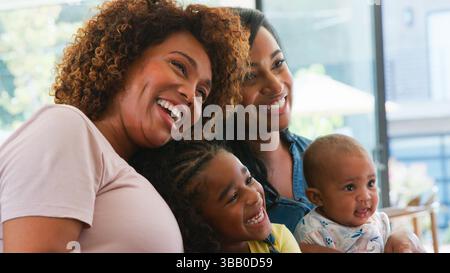 Multi-Generation Male African American Family Sitting On Sofa At Home Using Digital Tablet Stock Photo