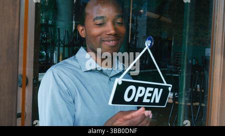Male Coffee Shop Owner Standing By Store Front Door Turning Round Open Sign Stock Photo