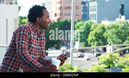 Businessman Standing Outside Office Building Using Mobile Phone With City Skyline In Background Stock Photo