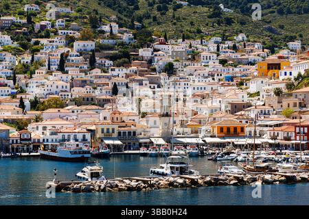 Panoramic view of the charming port town on the island of Hydra, Greece, with whitewashed houses, terracotta rooftops, a historic clocktower, and boat Stock Photo