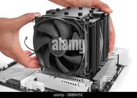 A person is installing a large black tower-style CPU cooler Stock Photo