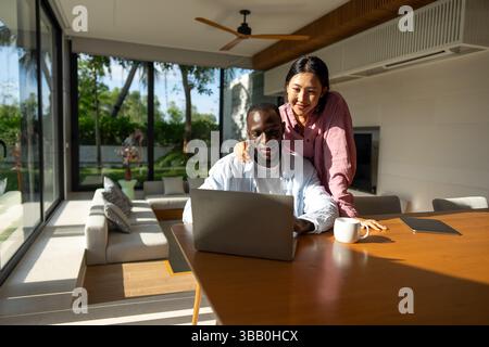 Multicultural couple working remotely, planning finances and investments online. Digital lifestyle Stock Photo