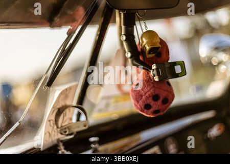 Close-up of fuzzy dice and other trinkets hanging from the rearview mirror of a classic car, adding a touch of vintage charm Stock Photo