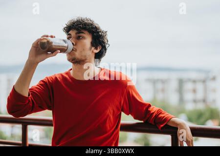 Young man enjoying a healthy smoothie drink on a balcony Stock Photo