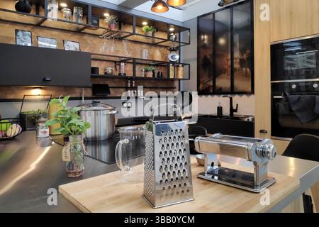 Modern, stylish kitchen with an industrial touch, featuring open black shelving, stainless steel appliances and a wooden accents. Stock Photo