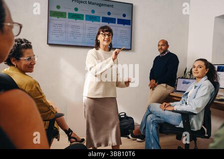 Project management team engaging in a collaborative meeting, discussing strategies with a digital presentation, and planning for a successful project Stock Photo