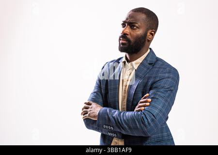 Portrait of worried and thoughtful businessman. Black man in business suit is standing with arms crossed and thinking. Stock Photo