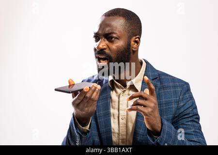 Close up portrait of angry businessman who is talking on mobile phone and threatens. Stock Photo