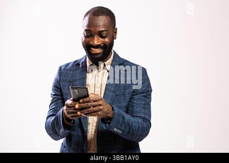 Portrait of happy and successful businessman. Black man in business suit is typing on smartphone. Stock Photo
