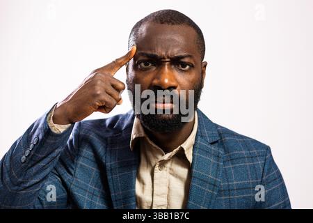 Portrait of serious and worried businessman. Black man in business suit is pointing at his head. Stock Photo