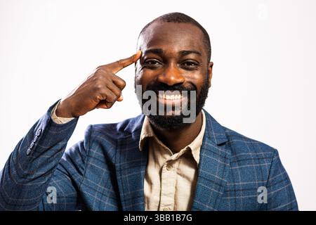 Portrait of happy and successful businessman. Black man in business suit is pointing at his head. He is having inspiration. Stock Photo