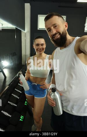 Couple with water bottles taking selfie after training in gym Stock Photo