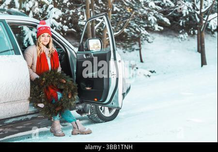 Yong woman travel by car in winter. Low temprature car care concept. Beautiful woman sits in a car coverd with snow. Stock Photo