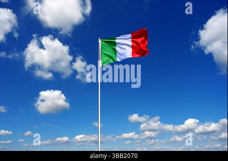 flag of Italy fluttering in the blue sky with cumulus clouds Stock Photo