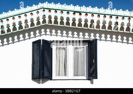 Wooden vintage window with dark shutters on the plastered stone wall. Exterior front side, facade of traditional Mediterranean stone house with wooden Stock Photo