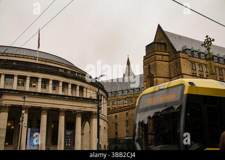 Iconic exterior of Manchester Central Library framed by gothic architecture and public transport on a cloudy day in the city center. Stock Photo