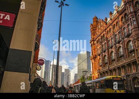 Late afternoon sunlight hits a row of historic red-brick buildings along a bustling Manchester street. Side view of grand Edwardian hotel, the Midland Stock Photo