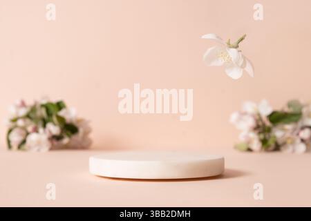 White empty marble platform and blurred cherry blossom flowers against soft peach background. Elegance and simplicity design. Space for design your pr Stock Photo