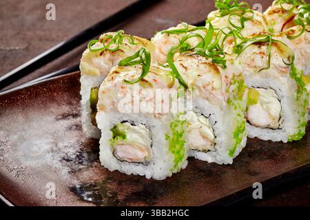 Sushi rolls covered with cream cheese and green tobiko on a plate Stock Photo