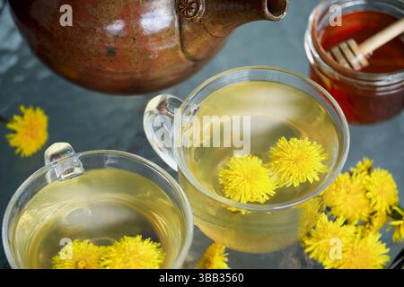 Overhead of two steaming hot cups filled with vibrant dandelion tea for herbal medicine. Selective focus with blurred background, Stock Photo