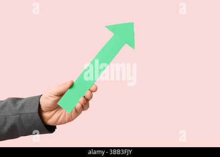 Businessman's hand with arrow pointing at something on pink background Stock Photo