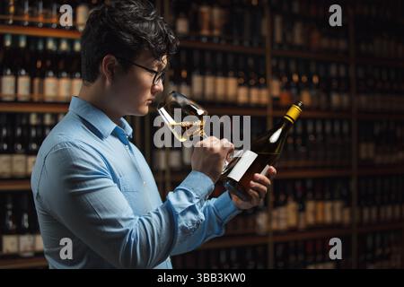 Professional Sommelier Evaluating Wine With Intense Focus In Cellar Setting Stock Photo