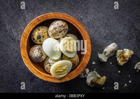 Boiled quail eggs in bowl on a black table. Top view. Stock Photo