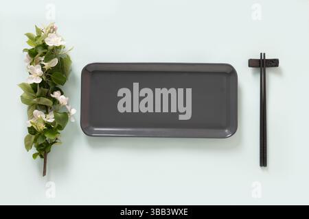 Empty rectangular gray plate for asian food with black chopsticks on blue background surface with spring branches. Asian style. View from above. Copy Stock Photo