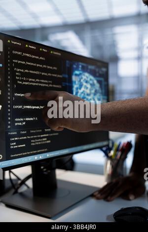 System administrator using machine learning applications to optimize server farm operations. IT expert pointing to PC monitor, implementing server virtualization in data center facility Stock Photo