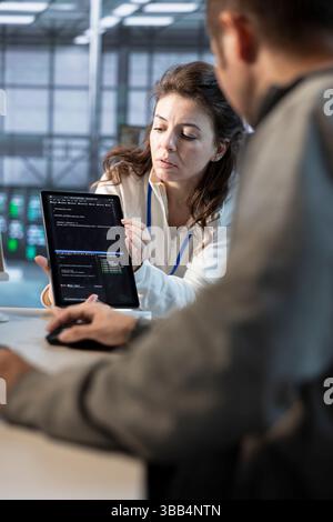 Team on engineers using tablet in data center, managing and optimizing IT infrastructure using network management skills. Server room coworkers upgrading gear with device, reducing operational costs Stock Photo