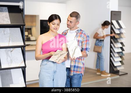 Couple discussing tile samples displayed on racks in home improvement store Stock Photo