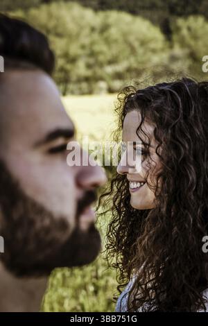 Vertical close up portrait of a couple laughing. man face out of focus in foreground and woman face focused in background Stock Photo