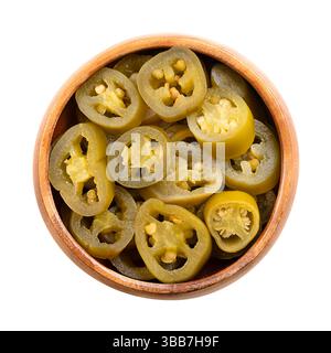 Pickled green jalapeno slices in a wooden bowl. Medium-sized hot, green chili peppers, cut into cross sections, pasteurized and preserved in brine. Stock Photo