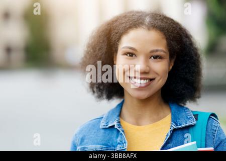 Closeup Portrait Of Cheerful African American female student wearing a denim jacket Stock Photo