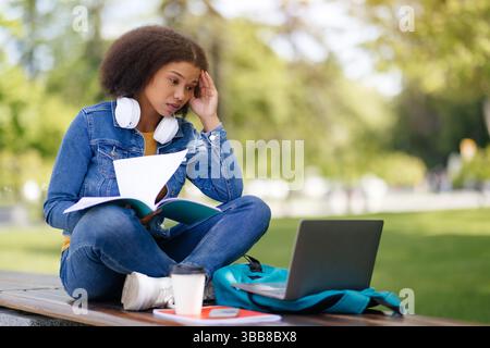 Stressed African American female student study with laptop outdoors Stock Photo