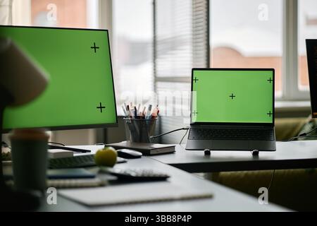 Multiple screens with tracking markers visible in modern office setting featuring gadgets and electronics surrounding workspace. Window in background Stock Photo