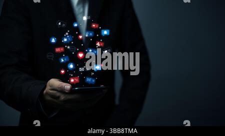 businessman holding a smartphone with floating social media icons, digital marketing commerce, online engagement, and social networking. mobile phone Stock Photo