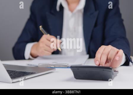 Accounting, finance work. Man using calculator. Laptop, pen, and paperwork. Calculating budget, analyzing data at his desk. Stock Photo