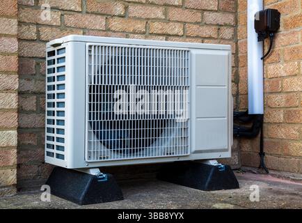 A single heat pump or compressor unit outside a modern house to provide air conditioning or warmth Stock Photo