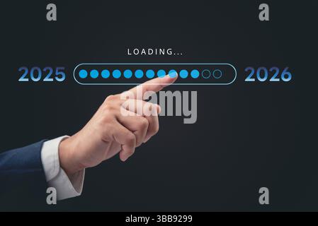 A professional hand interacting with a digital loading bar, marking the transition from 2025 to 2026. The concept represents progress, time, and futur Stock Photo