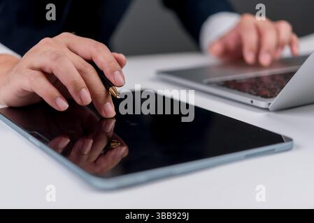 Businessman using tablet and pen for digital signature, with laptop on desk, representing paperless office, e-signature, online workflow and digital d Stock Photo