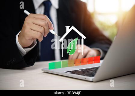 Sustainable housing concept with businessman evaluating energy chart on laptop, green building, environmental performance, smart eco home and clean en Stock Photo