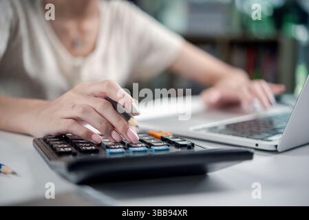 Businesswoman using a calculator and laptop for financial planning and budget management.Accountant analyzing financial data, calculating business exp Stock Photo