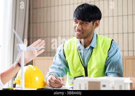 Sustainable Development Discussion. Engineers collaborating on renewable energy projects in a modern office. Stock Photo