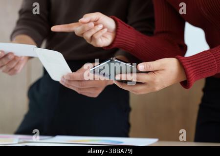 Business Collaboration and Communication. Two colleagues engaged in a discussion, sharing ideas and feedback over a smartphone. Stock Photo