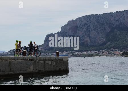 Mondello and its beach viewed from boat trip, near Palermo, Sicily - Cyclists gathering in Mondello harbour Stock Photo